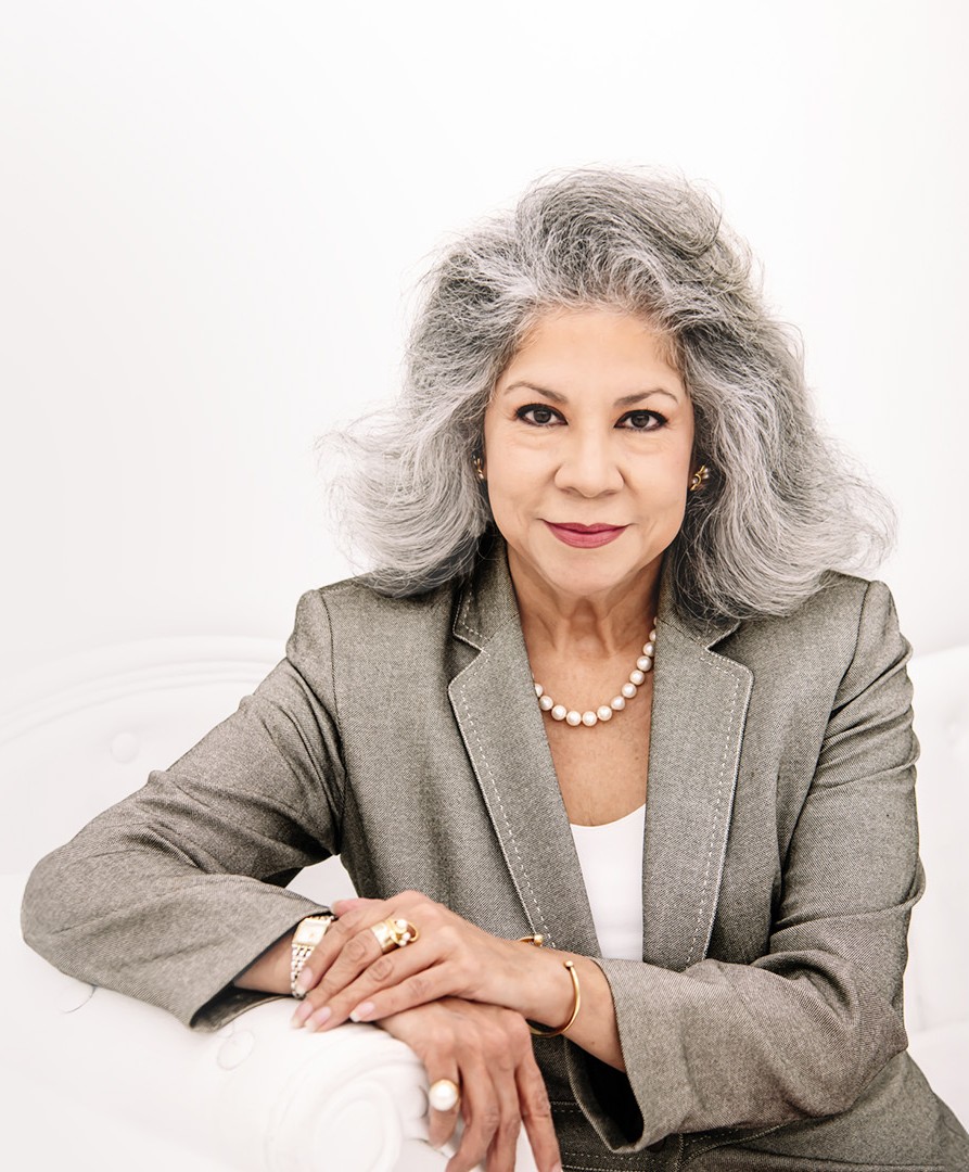 Lolita Smoak in a gray blazer leaning against a white chair